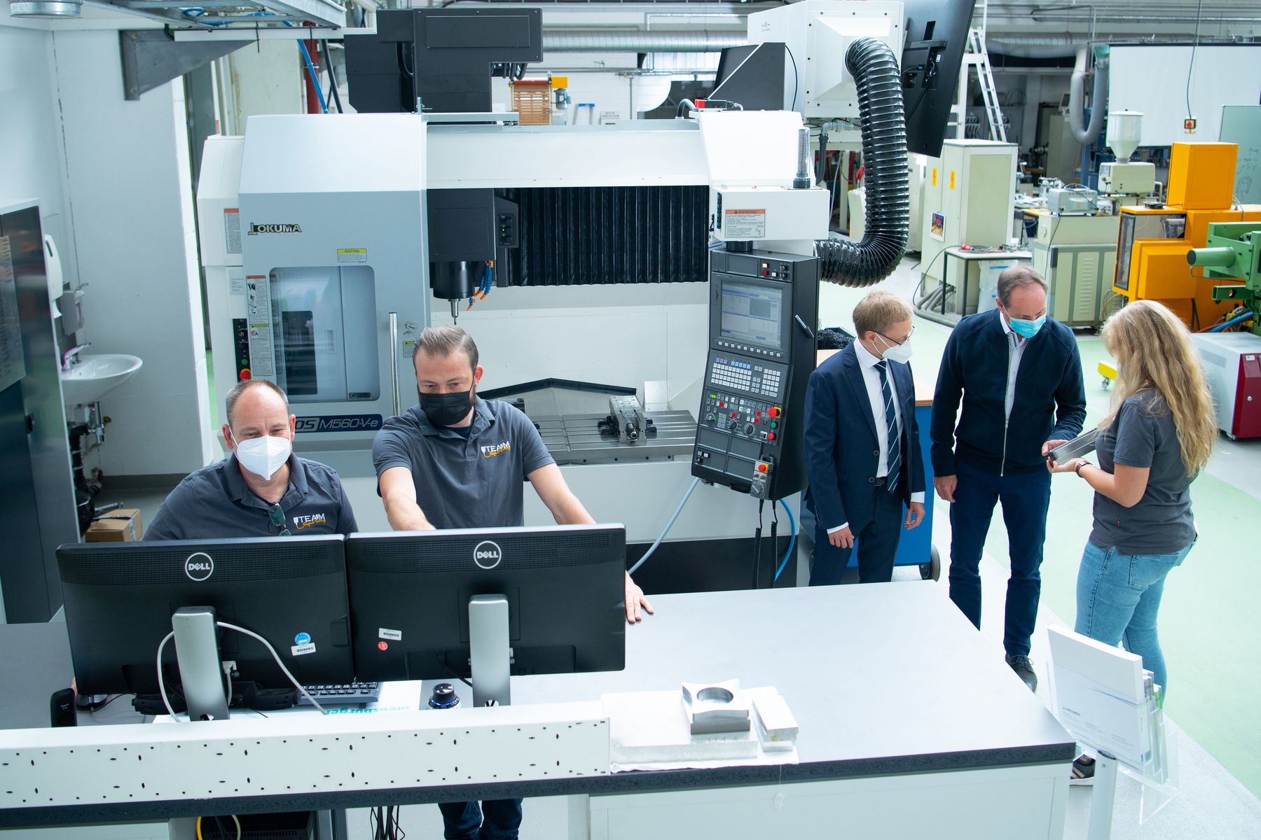 5 Menschen beim bedienen der Maschine
