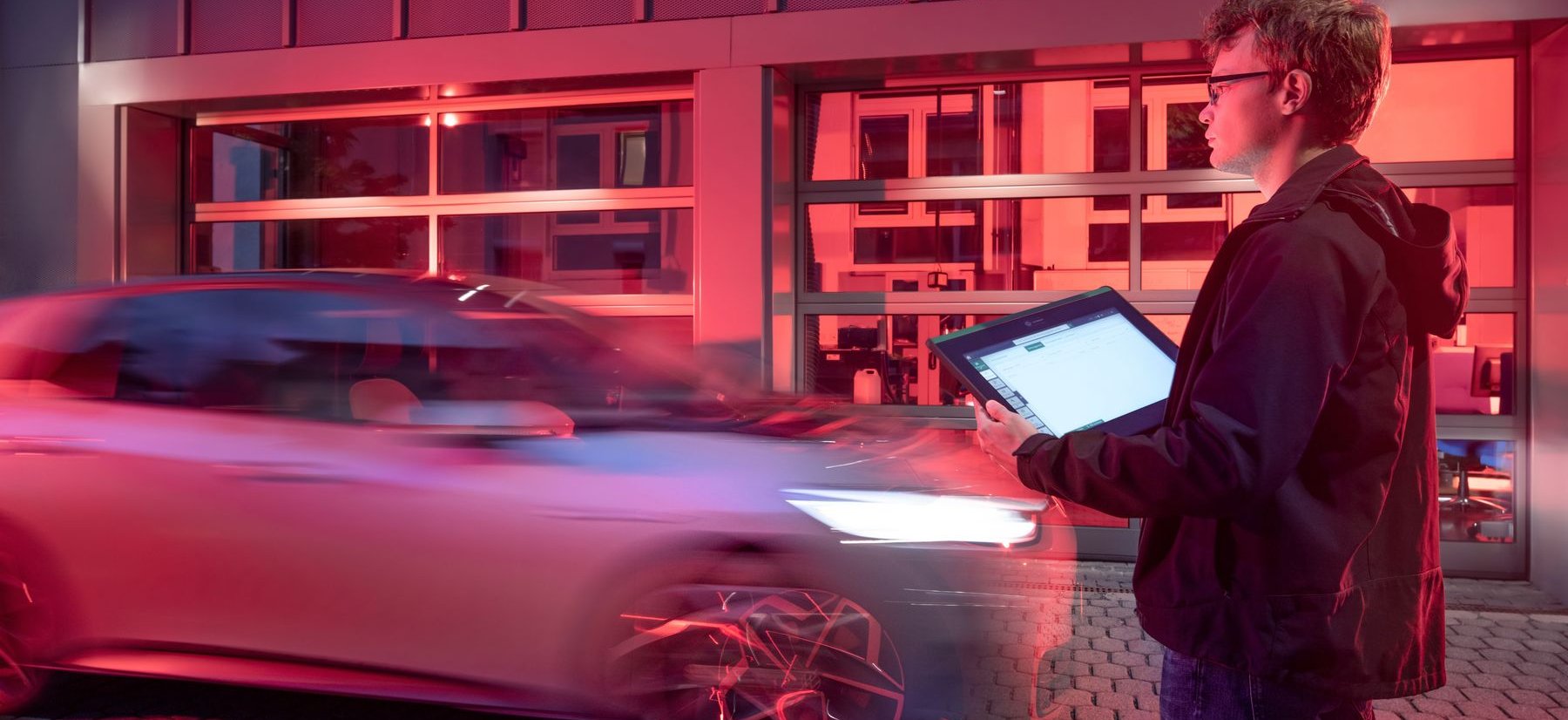 Ein Mitarbeiter der Forschungsgruppe mit Laptop vor einem einfahrenden Auto