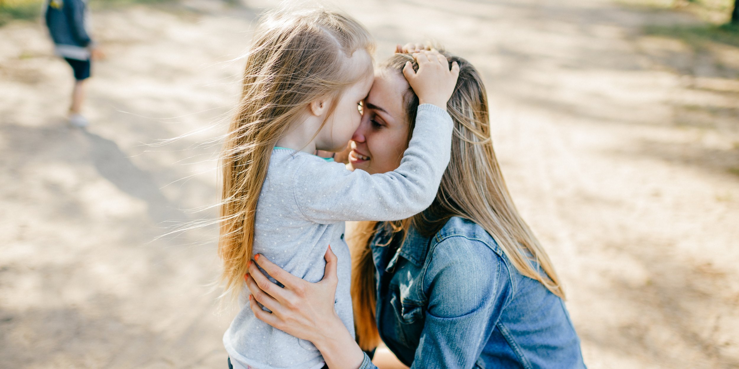 Mutter umarmt ihre kleine Tochter in einem Park