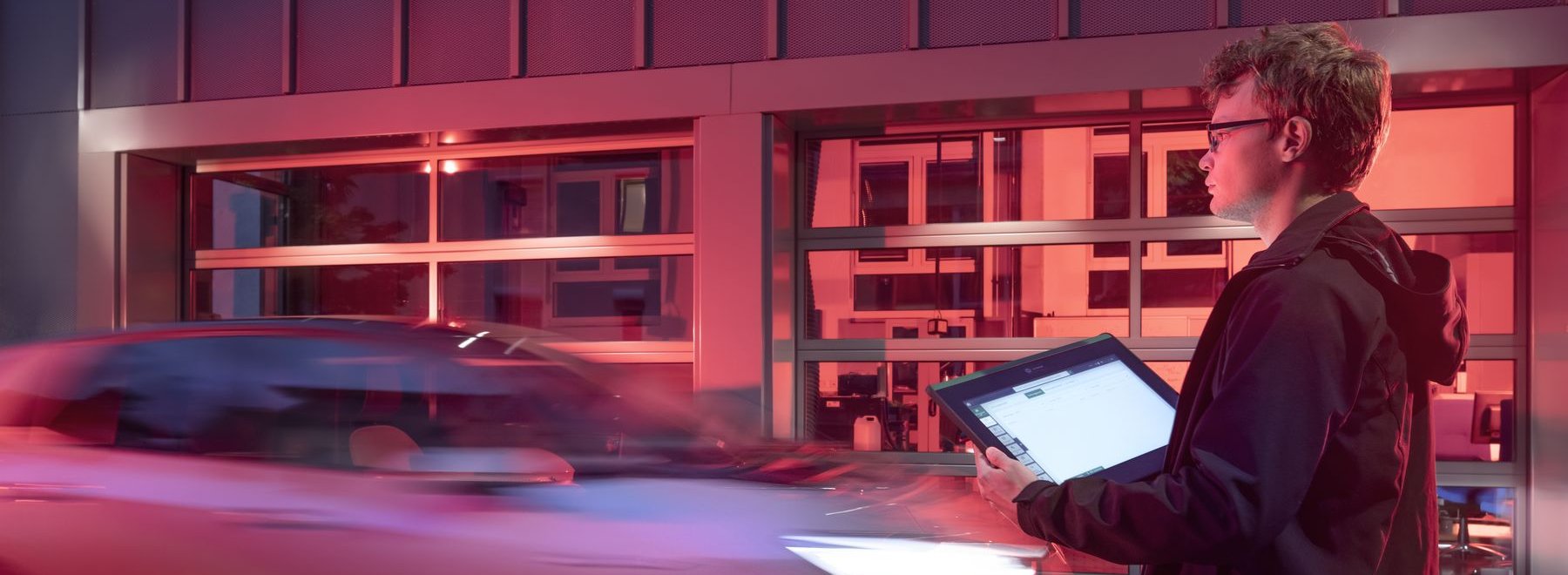 Ein Mann mit Laptop neben einem fahrenden Auto