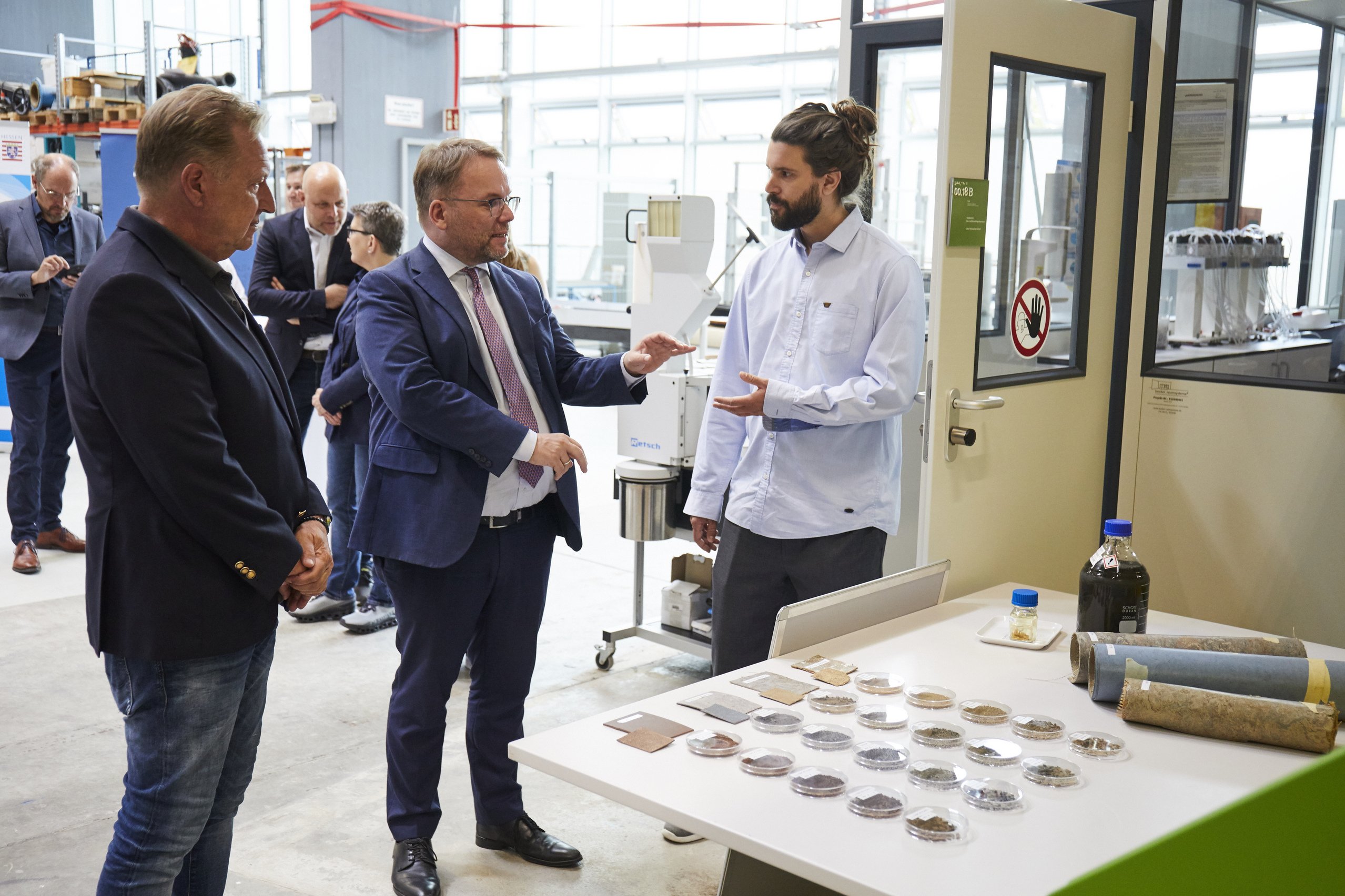 Student im Gespräch mit Minister vor einem Tisch mit verschiedenen Petrischalen