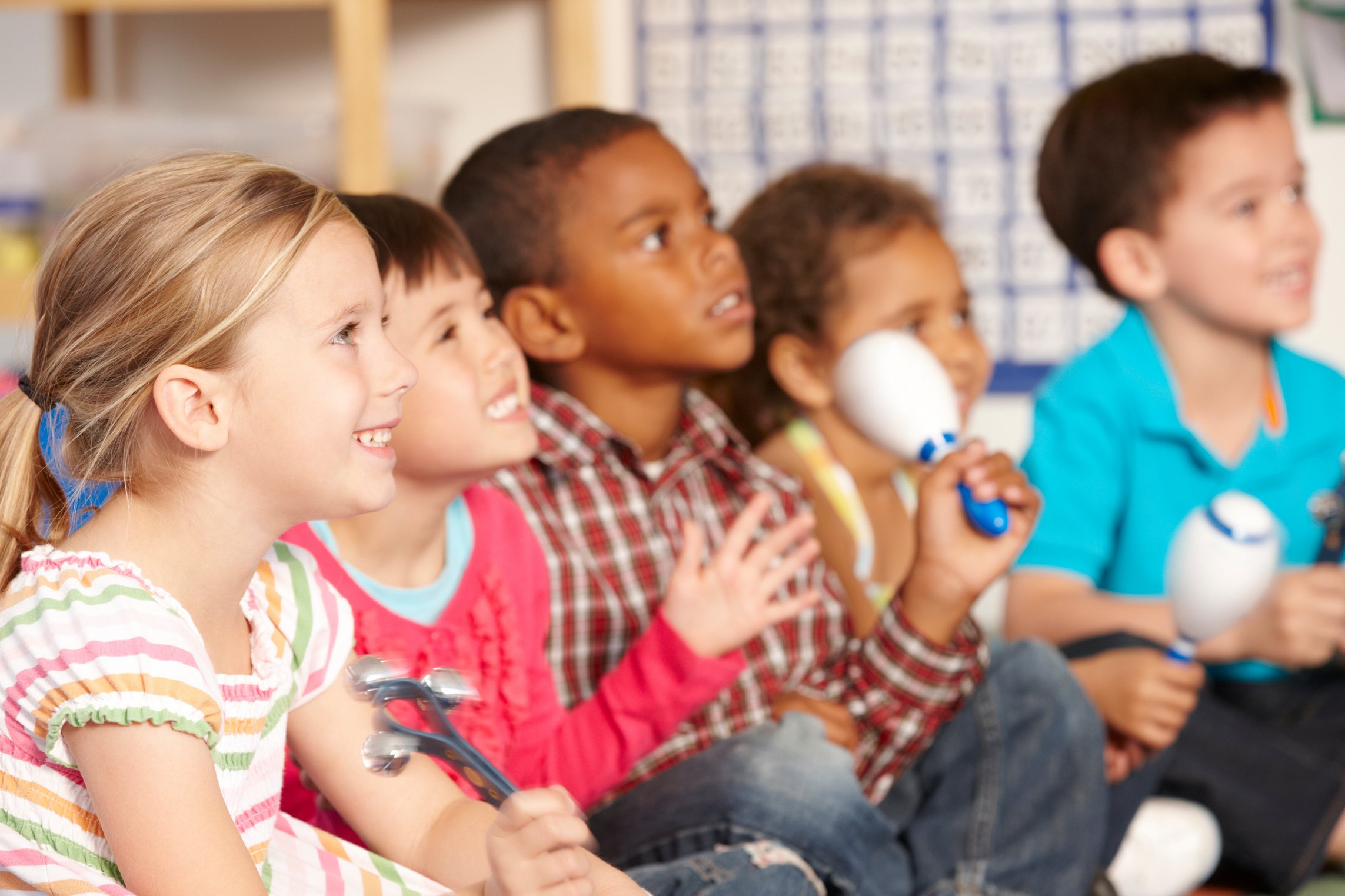 Kindegruppe musiziert am Boden sitzend und sichtbar fröhlich