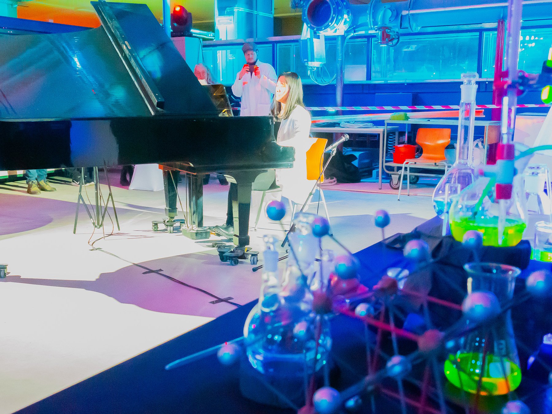 In blauen Fabrtönen beleuchtete Konzertfläche, Pianistin am Flügel