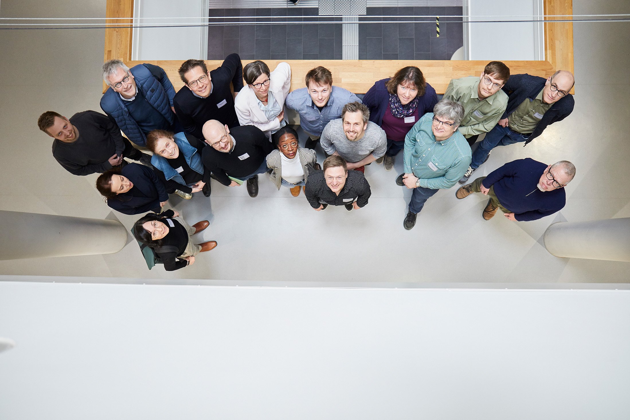 Gruppe von Workshop-Teilnehmenden im Erdgeschoss des CuB-Gebäudes mit Blick nach oben zum Fotografen