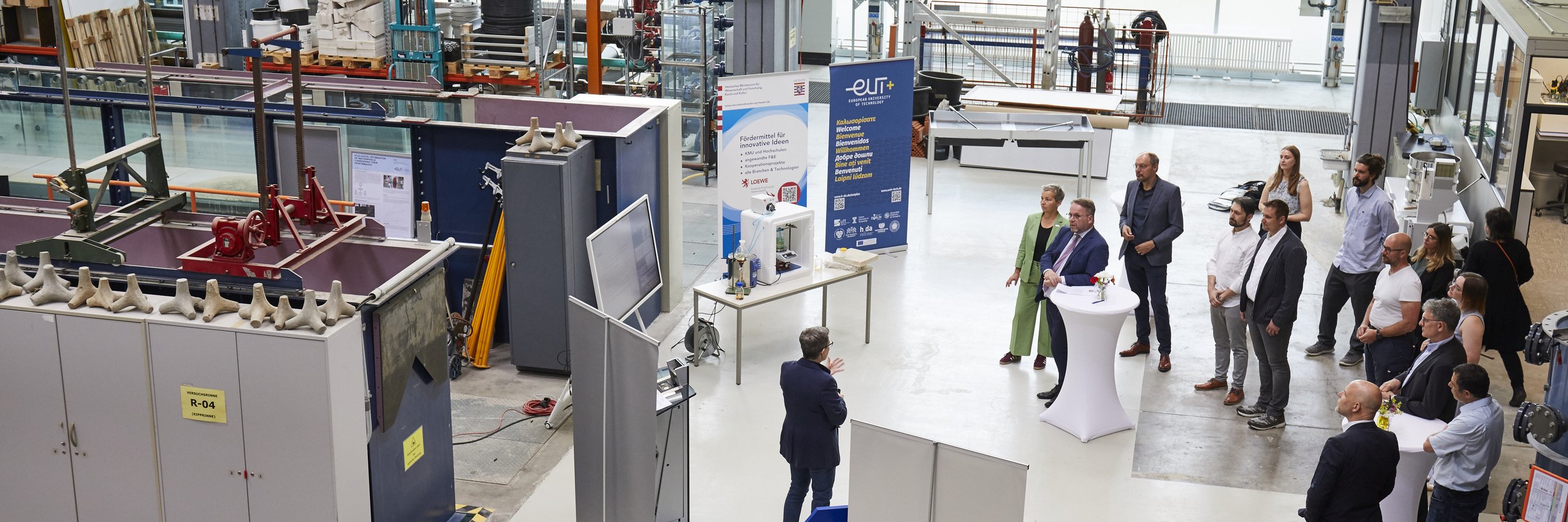 Menschen stehen im Halbkreis im Erdgeschoss der Wasserbauhalle
