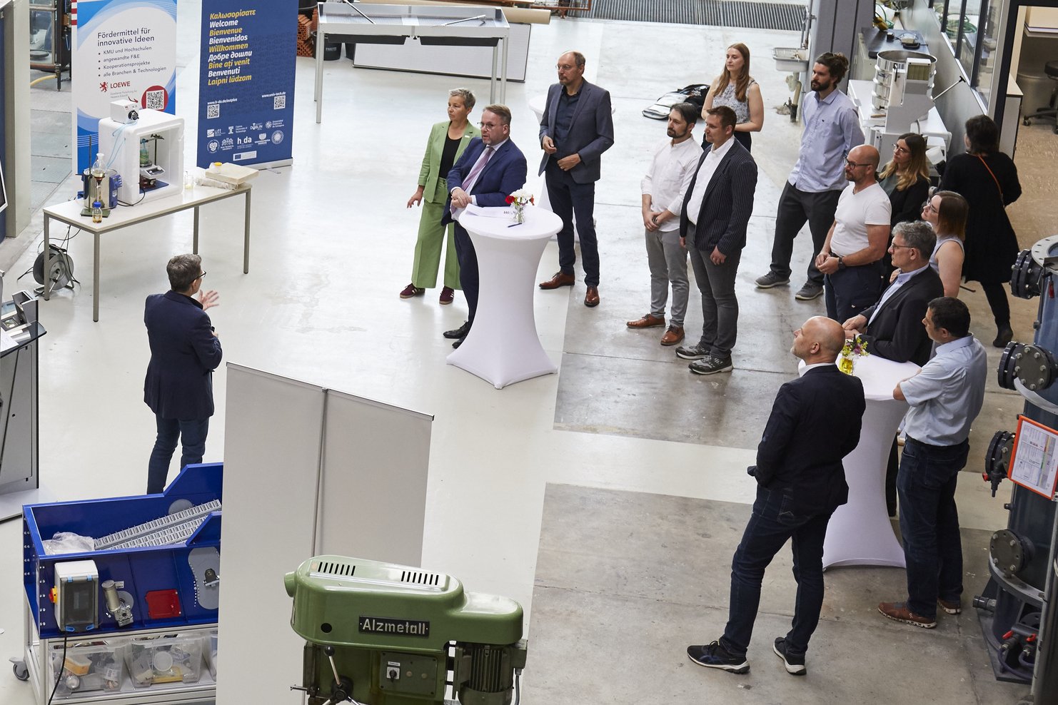 Menschen stehen im Halbkreis im Erdgeschoss der Wasserbauhalle beim Vortrag von Professorin Iris Steinberg
