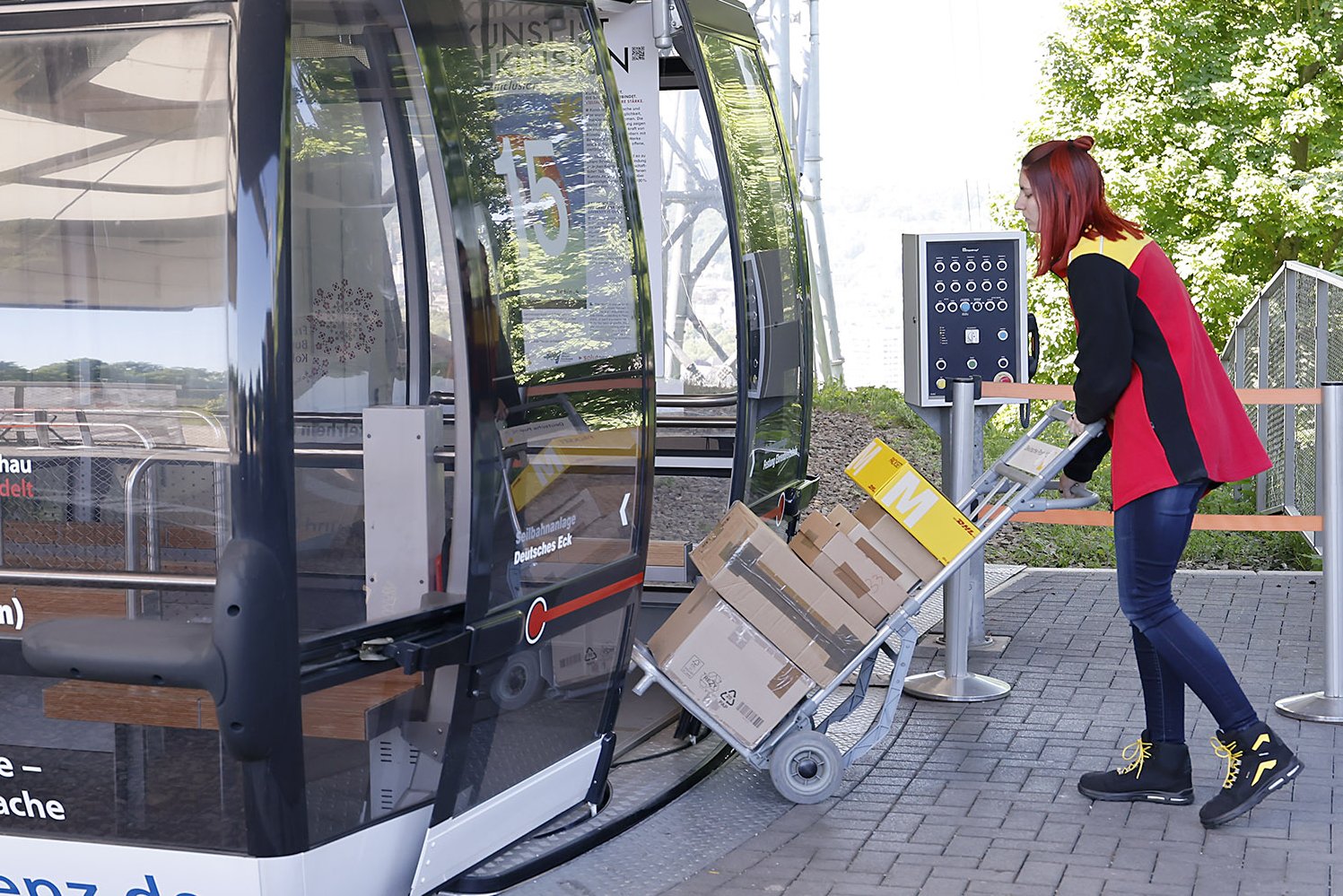 DHL-Botin lädt Pakete in eine Seilbahnkabine ein